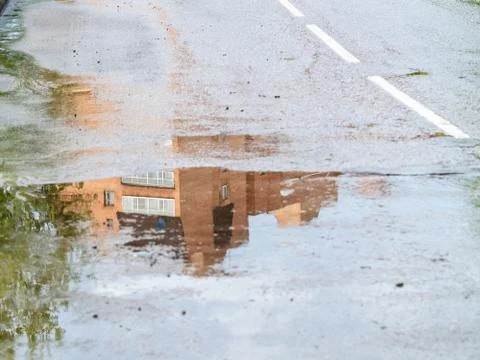Reflection of house in rain puddle on road Stock Photos