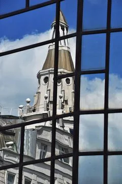 Reflection of an house with a tower in the window panes of a modern building Fotos de archivo