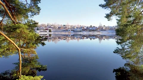Reflection of houses on calm lake water in winter with snow Stock Footage