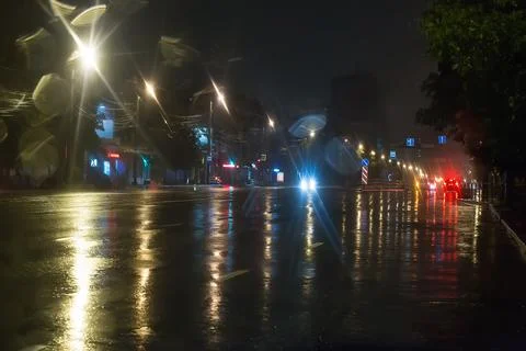 Reflection of lanterns and headlights on wet asphalt road. Stock Photos