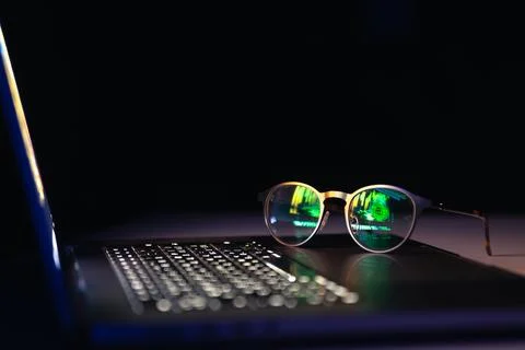 Reflection from a laptop in glasses on a dark background. 스톡 사진