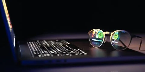 Reflection from a laptop in glasses on a dark background. 스톡 사진