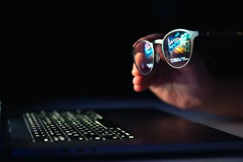 Reflection from a laptop in glasses on a dark background. 스톡 사진