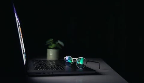 Reflection from a laptop in glasses on a dark background. 스톡 사진