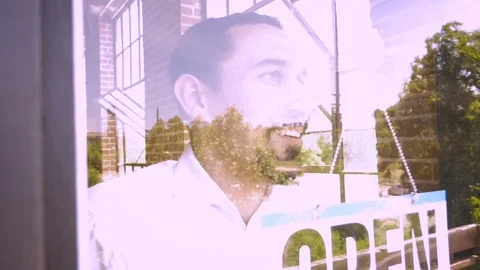 Reflection of latino man putting up open sign on his business in slow motion Video stock 78916412