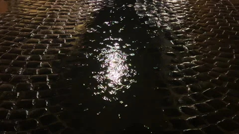 Reflection of light from a street lamp in a puddle of water during rain at night Vídeo Stock 295825364
