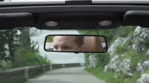 Reflection man face in rear view mirror. Young male tourist drive convertible Stock Footage 130696541