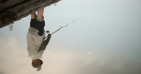 Reflection of a man fishing off the end of a dock Видео 120699604