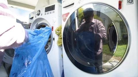 Reflection of man with gloves loading laundry Stock Footage 117433048
