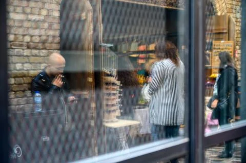 Reflection of a man smoking a cigarette while using a handheld device as shop Stock Photos