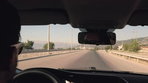Reflection of a man in sunglasses in the rearview mirror. Car is driving on the Stock Footage 204850705