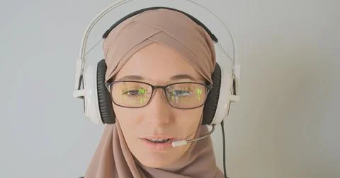 Reflection of the matrix code in glasses. Young woman in hijab is talking in Stock Photos