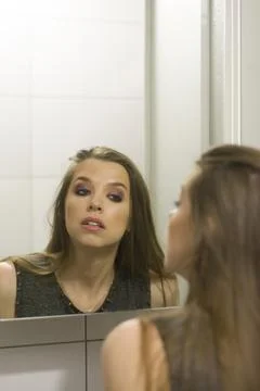Reflection in the mirror of a beautiful brunette with evening make-up Stock Photos