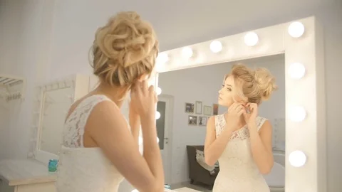 Reflection in a mirror of a beautiful girl putting on earrings close-up Stock Footage 74477825