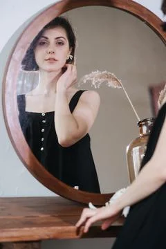 Reflection in a mirror of a cute sensual young woman in a black dress. Stock Photos