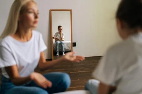 Reflection in mirror detached sad little girl during stressed mother scolding Stock Photos
