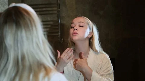 Reflection in the mirror of the face of an unhappy young blonde woman in home Stock Footage 232472229