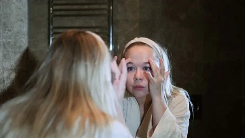 Reflection in the mirror of the face of an unhappy young blonde woman in home Stock Footage 232842887