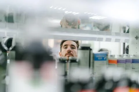 Reflection in the mirror of a man choosing medication at a pharmacy Stock Photos