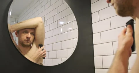 Reflection in the mirror of a man shaving his armpits with an electric trimmer Vídeos de archivo 264019090
