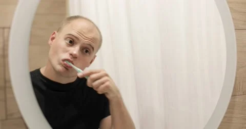 Reflection in mirror of man who brushing his teeth in bathroom in morning. Stock Footage 137489761