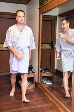 Reflection in the mirror mocks the man in bathrobe Stock Photos