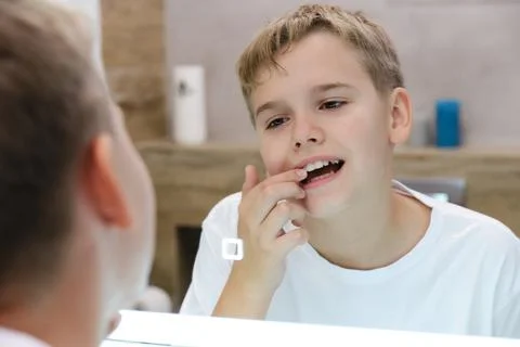 Reflection in the mirror of a schoolboy looking at his teeth. Foto stock