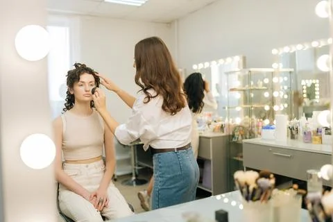 Reflection on mirror of unrecognizable female make-up artist applying cosmetic Stock Photos