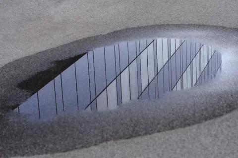 Reflection of modern building facade in a water puddle Stockfoto's