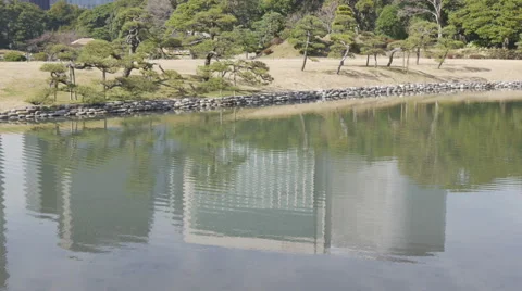 Reflection of modern buildings over a lake at a traditional Japanese garden. Stock Footage 61750355