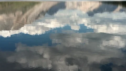 Reflection of a mountain, blue sky and clouds in a calm lake with small ripples Stock Footage 293512533