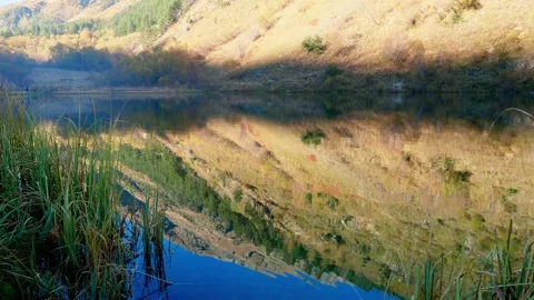 Reflection of mountain side covered with dry yellow grass in mountain lake Stock Footage 145613021