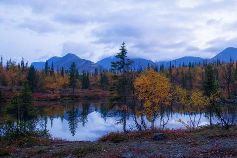 Reflection of mountains and clouds in the calm surface of the lake. Peaceful Stock Photos