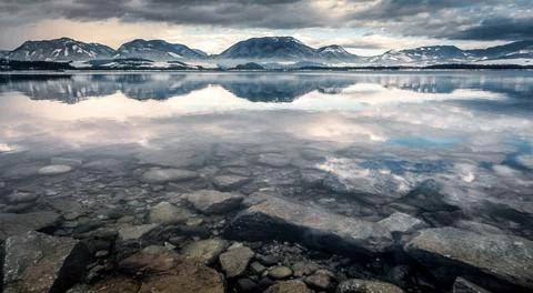 Reflection of mountains and dark sky on water surface Stock Photos