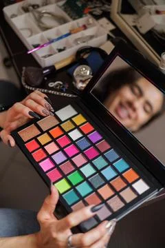 Reflection of a non-binary person in the mirror putting on makeup before goin Stock Photos