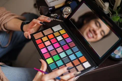 Reflection of a non-binary person in the mirror putting on makeup before goin Stock Photos