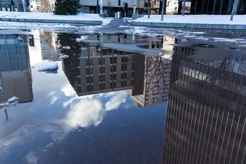 Reflection of office buildings in a puddle on the ground Foto stock