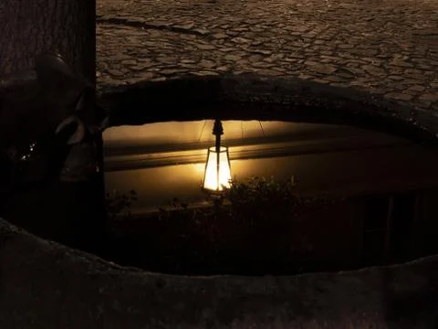 Reflection of an old lamp on the water surface at night Stock Photos