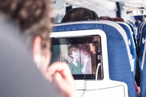 Reflection of a passenger on an airplane touch screen monitor while watching Stock Photos