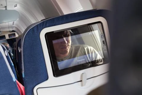 Reflection of a passenger on an airplane touch screen monitor while watching Stock Photos