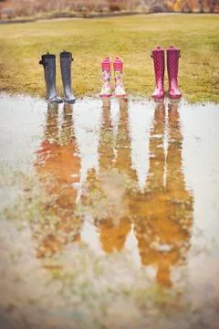 Reflection of people from rain boots in puddle 스톡 사진