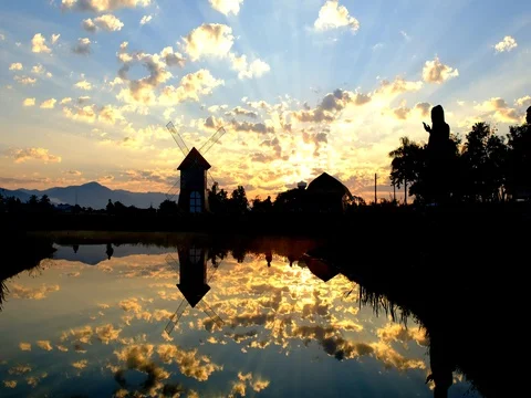 Reflection of people in silhouette walking around a lake at sunset Stock Footage 70975031