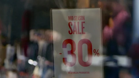 Reflection of people walking in street on a mid season 30% sale red sign Stock Footage 112080857