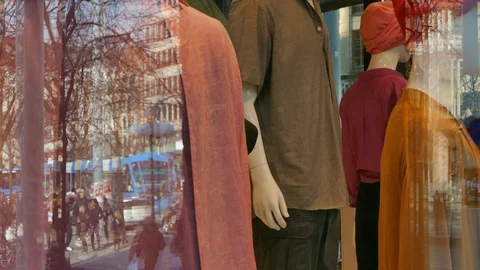 Reflection of people walking in street on the window of a store selling cloths Stock Footage 112080448