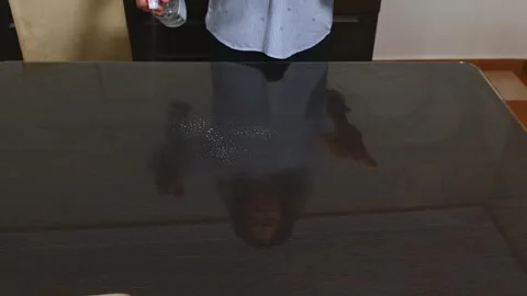 Reflection of person cleaning glass table in modern dining area Stock Footage 297354289