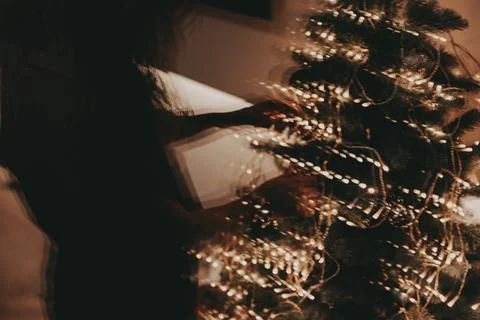 Reflection of a person decorating a Christmas tree with lights and ornaments Stock-Fotos
