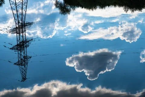 Reflection of a power line and dark cumulus clouds in the water. Stock Photos