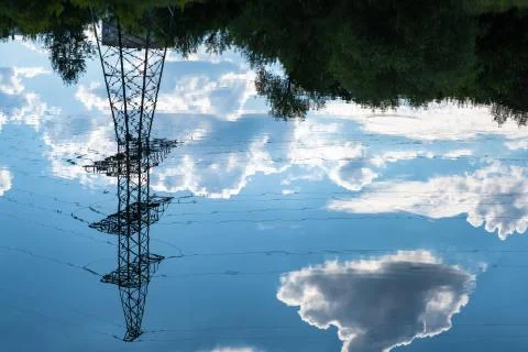Reflection of a power line and dark cumulus clouds in the water. Stock Photos