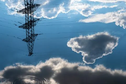Reflection of a power line and dark cumulus clouds in the water. Stock Photos