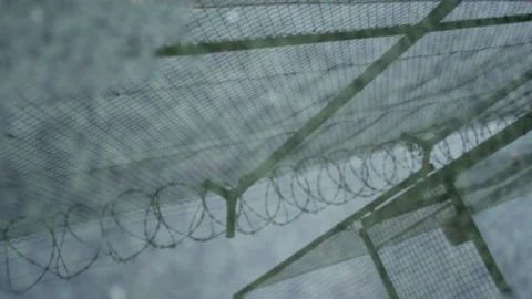 Reflection of a prison chain link fence with barbed wire in a puddle Stock Footage 165052308